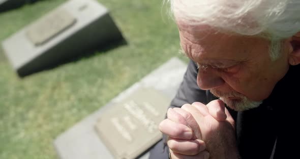 Sad Old Gray Haired Man Prays on the Grave at the Cemetery