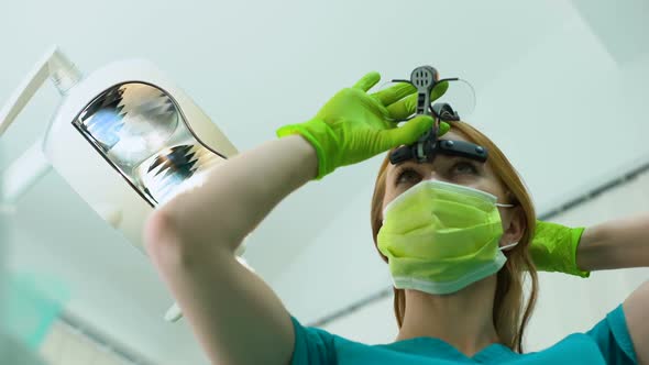 Young Woman Dentist in Magnifying Glasses Examining Oral Cavity, Patient POV