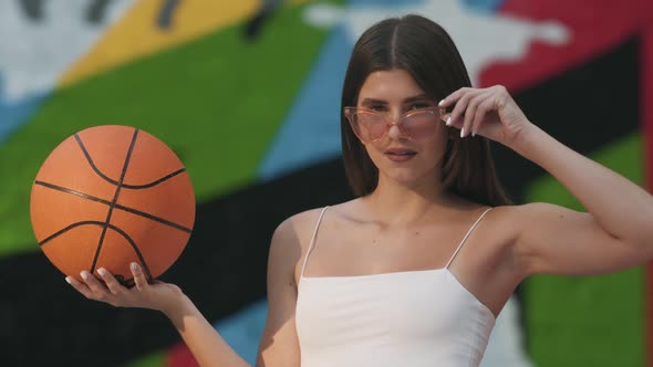 Confident Brunette Gorgeous Woman in Sunglasses Posing with Orange Basketball Ball