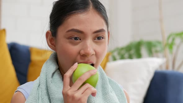 Young Asian woman healthy happy eating apple in the living room at home.