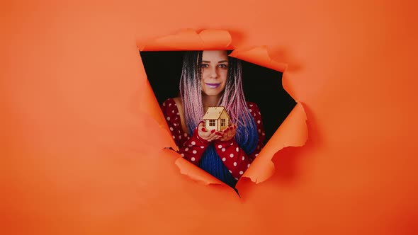 Woman with Toy House Looking Through Hole in Paper