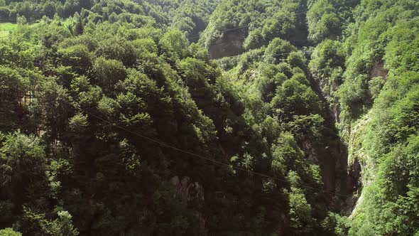 Aerial view of a person flying over the forest in zip-line at Slovenia