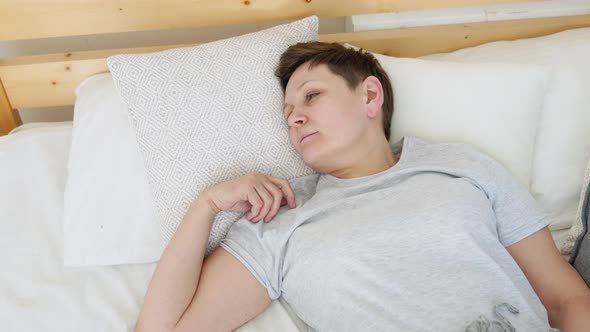 Mature Woman Falls Asleep in a Cozy Bed