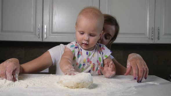 Young Mother and Her Little Daughter Preparing Dough on the Table