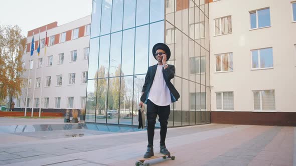 Young African Black Hipster Businessman Riding Longboard and Talking on Phone