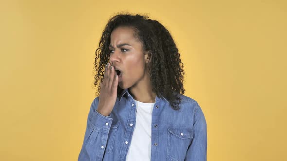African Girl Yawning and Stretching BodyIsolated on Yellow Background