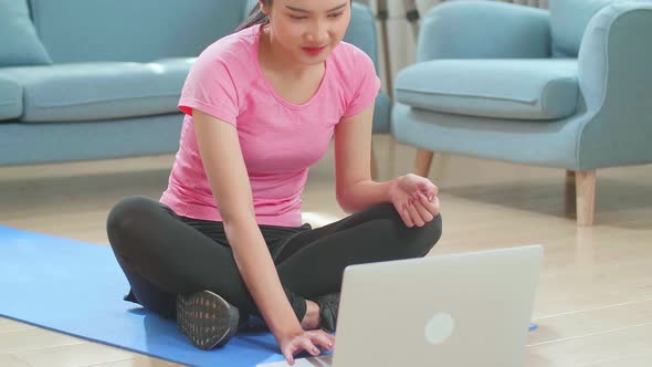Asian Woman In Sportswear Is Sitting On The Floor Using A Laptop At Home In The Living Room