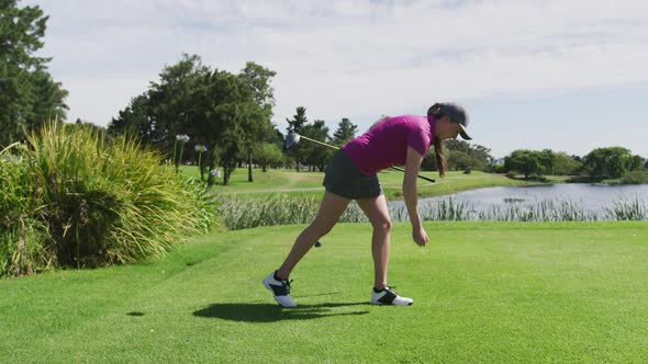 Caucasian woman playing golf putting a ball on a ground