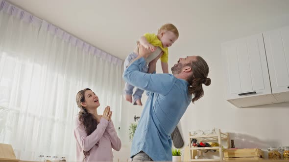 Caucasian happy loving parent play with baby toddler in living room spend time together as a family.