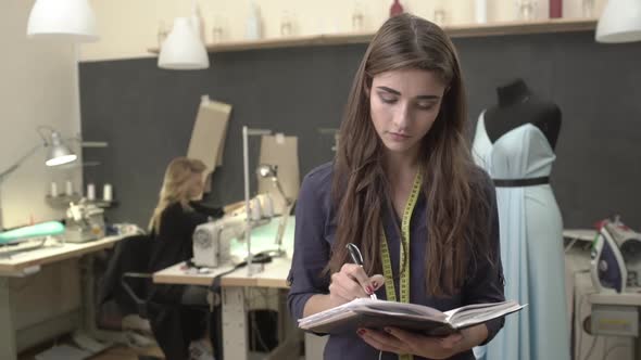 Beautiful Caucasian Female in Dark Blue Shirt and Long Brown Hair Making Notes Showing Ok Standing