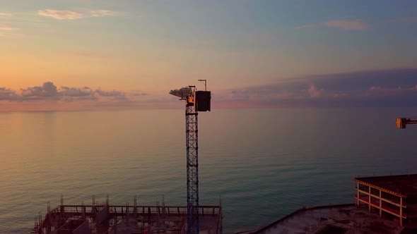 crane at sunset from a bird's-eye view, sun's rays pass through crane structure.