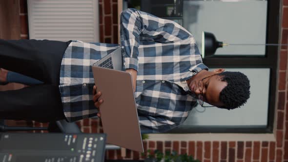 Vertical Video Portrait of African American Programer Standing Working on Laptop Looking Up and