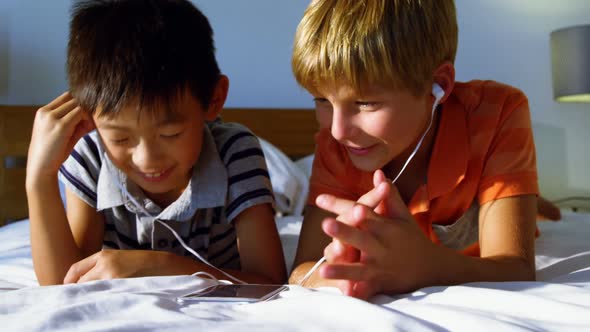 Siblings using mobile phone in bedroom