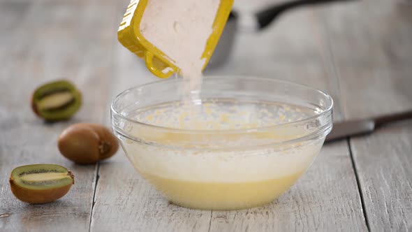 Adding flour to the dough. Chef hands pouring white flour to the dough in bowl.	