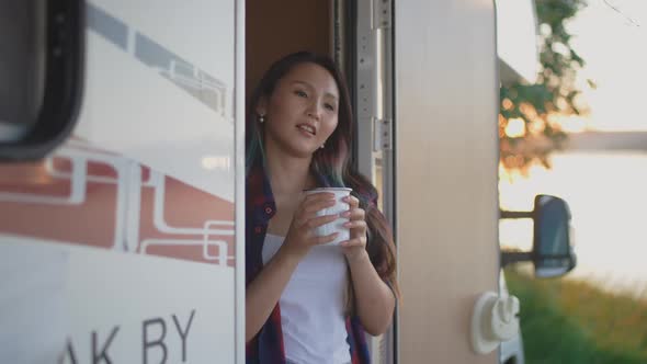 Asian Female is Resting in Nature Near the Lake Standing Near a Mobile Home and Enjoying Nature