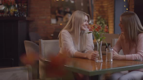 Happy Mother and Daughter Chatting in Cafe