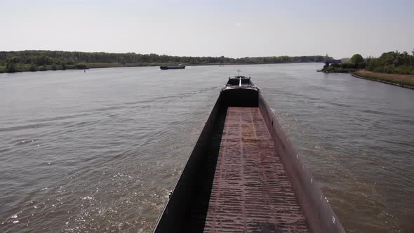 Vacant Storage Deck Of A Barge Ship Sailing On Calm River During Sunny Morning. - Aerial Shot