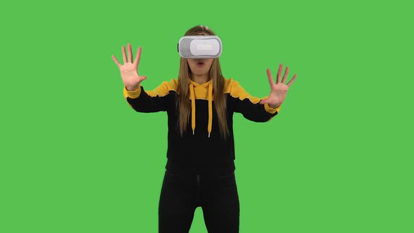 Modern Girl in Yellow Hoodie with Virtual Reality Headset or 3d Glasses. Green Screen