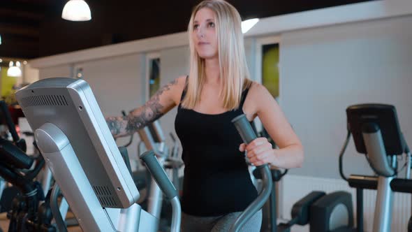 Young and Sexy Girl is Running on a Stepper at the Gym