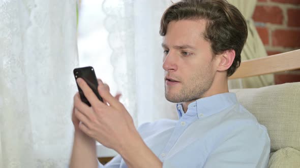 Portrait of Young Man Celebrating Success on Smartphone