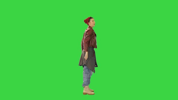 Young Girl in Stylish Clothes Dances with Her Arms Raised on a Green Screen Chroma Key