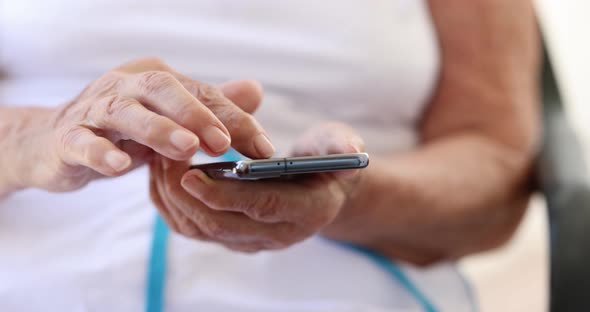 Hands of Elderly Woman with Modern Smartphone