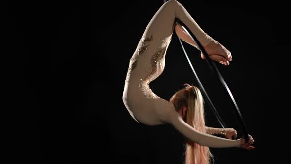 Flexible Slim Aerial Gymnast Performing Gazelle on Air Hoop at Black Background