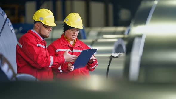 Two Workers in Production Plant As Team Discussing Industrial Scene in Background