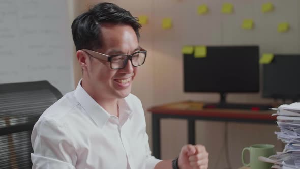 Close Up Of Happy Asian Man Celebrating Finishing Working With Documents At The Office