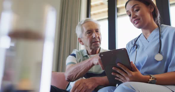 Animation of biracial female doctor with tablet talking with caucasian senior man