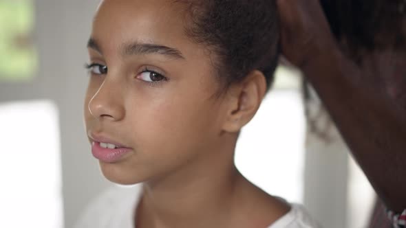 Headshot Beautiful Teenage African American Girl with Brown Eyes Indoors with Male Hands Making