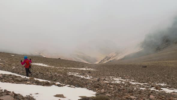 Tourist backpacker descending from the snow covered mountain, High Atlas, Morocco