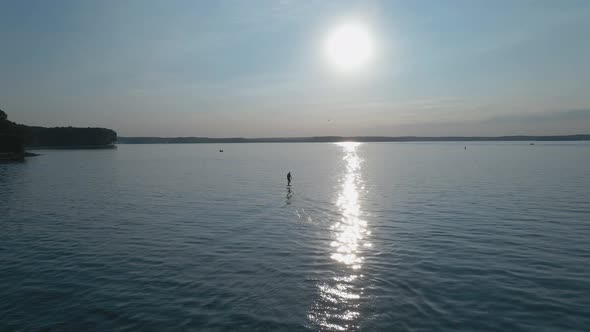 Man Riding on a Hydrofoil Surfboard on Large Blue Lake in Sunny Weather