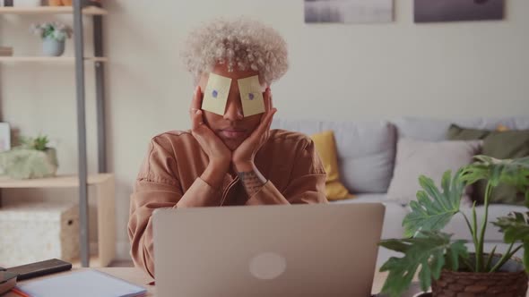 Tired African Woman Sleeping at Workplace with Stickers with Drawn Open Eyes