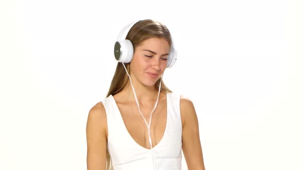 Beautiful Female in Headphones Listening To the Music with Fluttering on the Wind Hair Over White