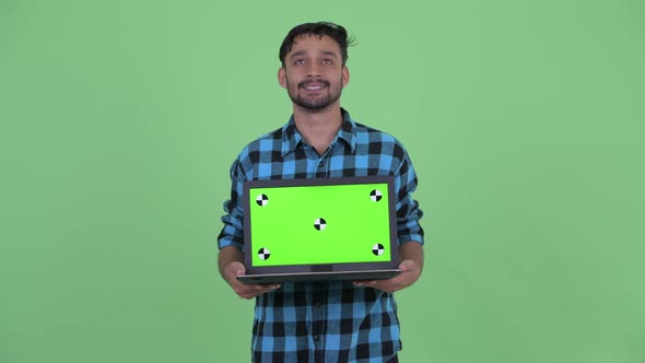 Happy Young Bearded Persian Hipster Man Thinking While Showing Laptop