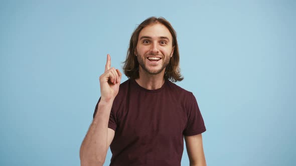 Young Bearded Male Came Up with an Idea Raising His Forefinger Up and Smiling Posing on Blue