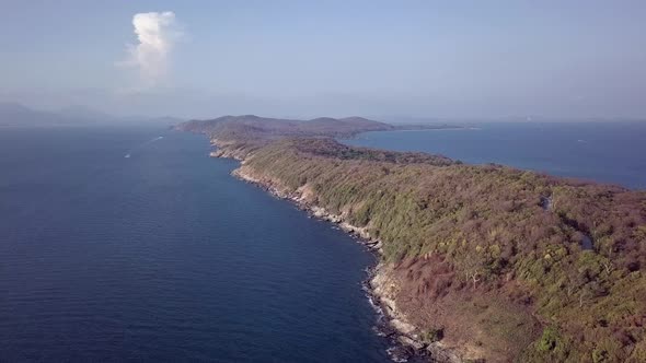Aerial: a high altitude paning shot of a beautiful tropical landscape,  a remote island covered with