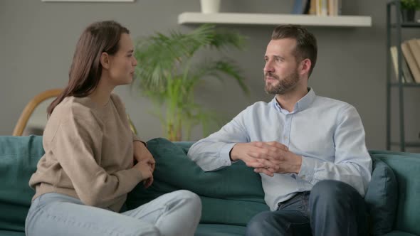 Happy Couple Having Conversation While Sitting on Sofa