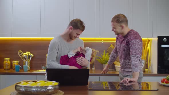 Joyful Gay Couple Playing with Child in Kitchen