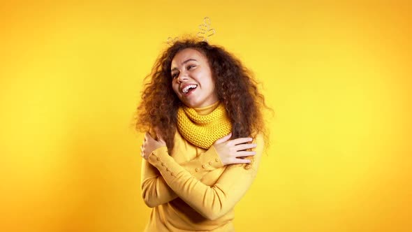 Young Cute Girl Smiling and Dancing on Yellow Background. Woman in Deer Horns.