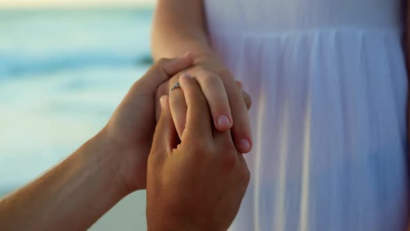 Man putting ring on woman finger at beach 4k