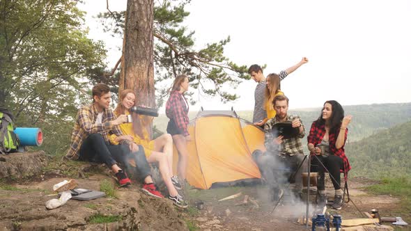 Young Positive Tourists Camped on Top of Mountain with Beautiful View