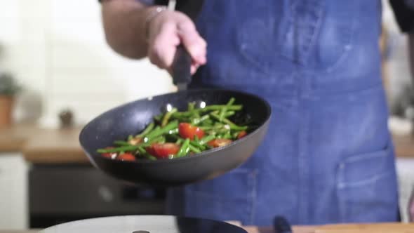 Chef roasts grilled vegetables in pan and effectively mixes tosses ingredients