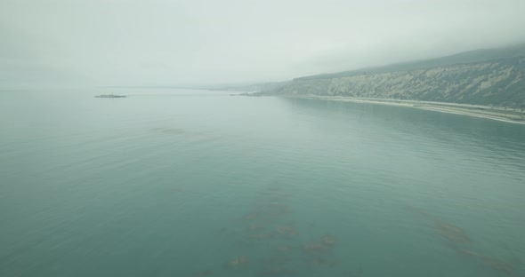 Helicopter aerial shot zooming from California coastline toward pier, foggy day
