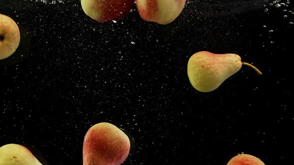 Ripe Fruits Red and Yellow Pears and Apples Falling Into Water Splash Air Bubbles Black Background