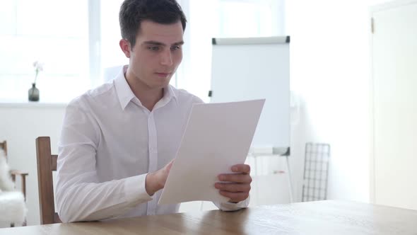 Successful Businessman Reading Documents and Celebrating Win