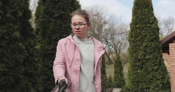 a beautiful girl in a light sweater and a pink jacket holds a dog leash that pulls