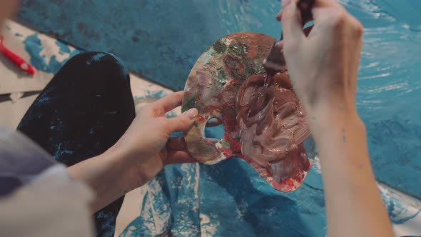 The Artist Vigorously Mixing Paint on a Palette