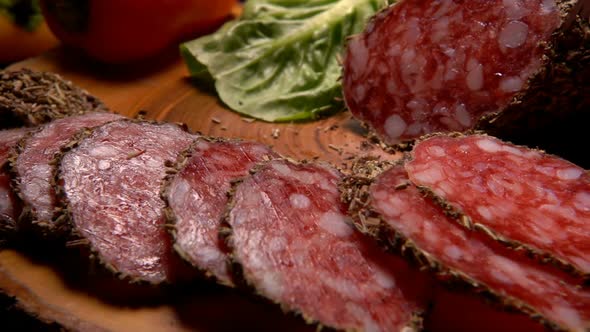Fork Takes Slices of Dried Sausage in Herbs
